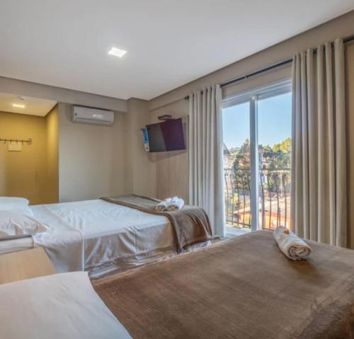 a hotel room with two beds and a large window at Villa di Cavi Hotel in Gramado