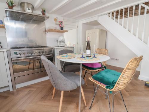 a kitchen with a table with chairs and a bottle of wine at The Studio Cottage in Denbigh