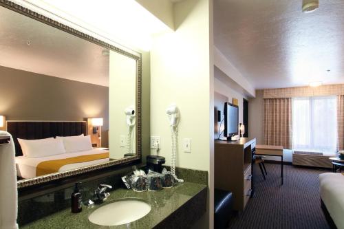 a hotel room with a bed and a mirror at Oxford Suites Spokane Valley in Spokane Valley