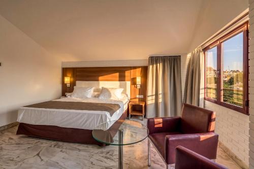 a hotel room with a bed and a chair at Spa Jardines de Lorca in Lorca