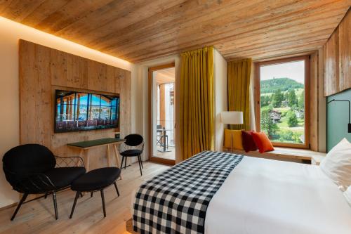 a bedroom with a bed and a desk and chairs at HOTEL de LEN in Cortina dʼAmpezzo