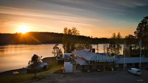 a house on a lake with the sunset in the background at Hotel Lahnajärvi in Lahnajärvenkylä