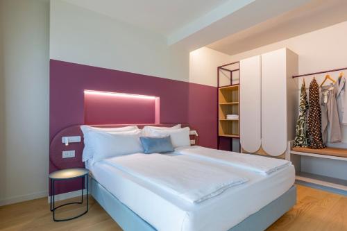 a bedroom with a large bed with a purple wall at Borgo di Lazise - Adults friendly in Lazise