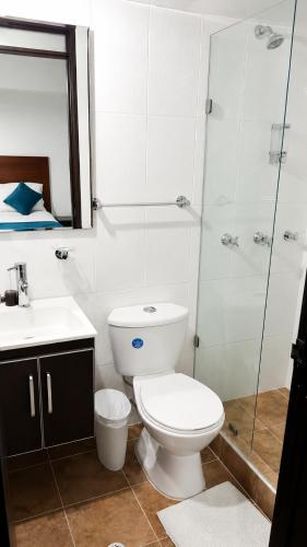 a bathroom with a toilet and a glass shower at Hotel Casa Lamay in Bogotá