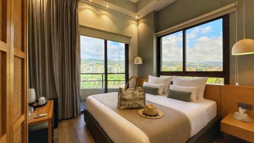 a hotel room with a bed with a large window at Be Batroun in Batroûn