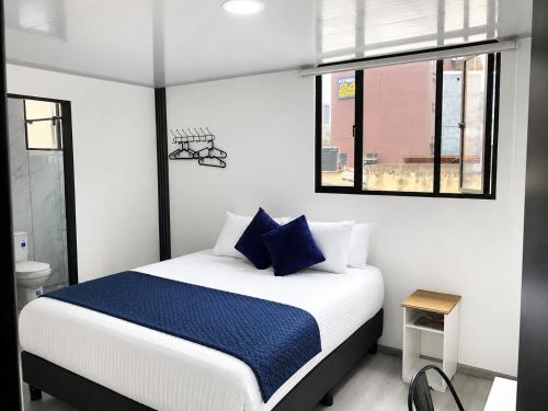 a bedroom with a large bed with blue pillows at Hotel Casa Lamay in Bogotá