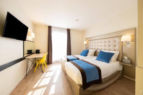 a hotel room with two beds and a flat screen tv at Best Western Hotel du Chateau Maisons Laffitte in Maisons-Laffitte