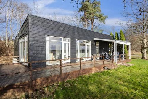 a black house with a deck and windows at Luxury Lakeside Retreat in Ringsted