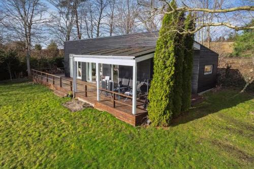 a small black house with a deck in a field at Luxury Lakeside Retreat in Ringsted
