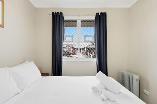 a bedroom with a white bed and a window at Kings Corner in Sandy Bay