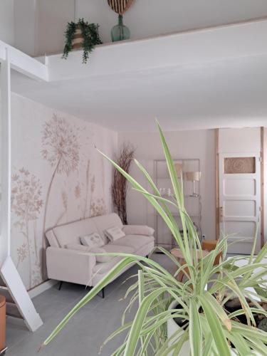 a living room with a couch and a plant at Chemin du vieux Puits in Surgères