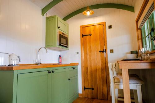 a kitchen with green cabinets and a sink at Northcombe Farm Shepherd's Hut in Germansweek