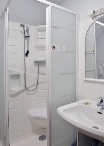 a white bathroom with a shower and a sink at Logis Hôtel Auberge de la Gabrière in Lingé