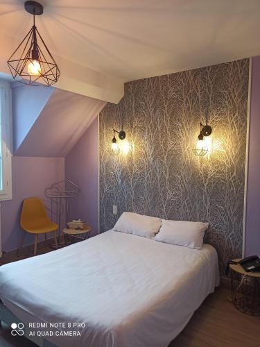 a bedroom with a bed and two lights on the wall at Logis Hôtel Auberge de la Gabrière in Lingé