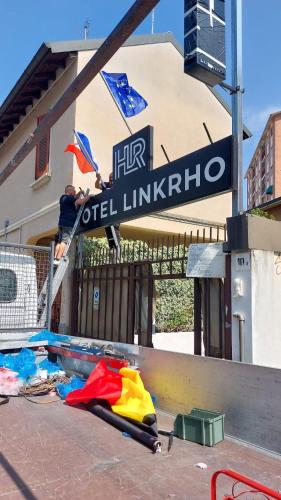 Ein Mann sitzt auf einem Schild vor einem Gebäude in der Unterkunft Hotel Link Rho in Rho