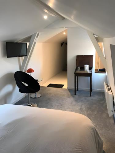 a bedroom with a bed and a chair and a desk at La maison de Yan in Cognac
