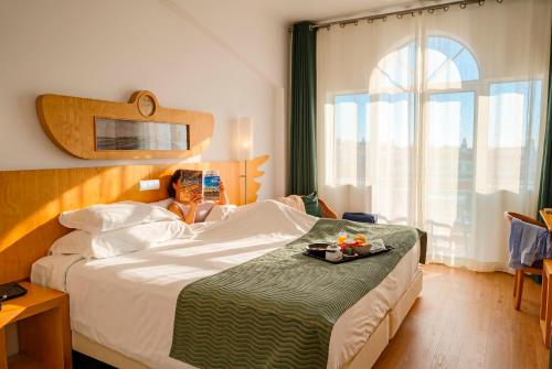 a bedroom with a bed with a tray of food on it at Hotel Ponta Delgada in Ponta Delgada