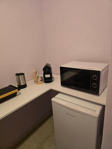 a microwave on a counter next to a trash can at Quiet Room in Florina