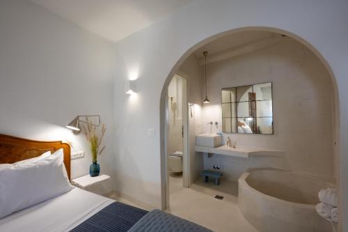 a bedroom with a bed and a tub in a bathroom at Arvanitis Cave Village in Akrotiri