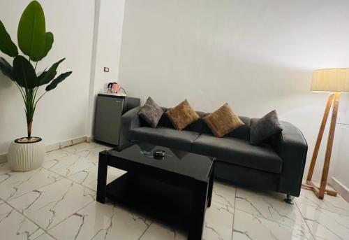 a living room with a black couch and a table at Neat & Modern Studio 2Mins Pyramids - Royal desert Inn in Cairo