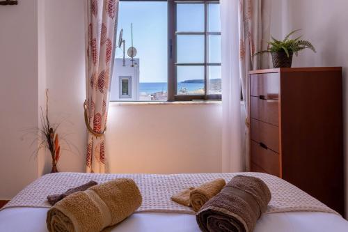 a bedroom with a bed with a window and towels at Casa Espadinha in Salema