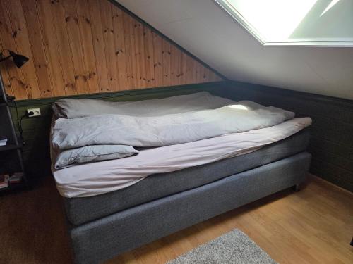 a unmade bed in a room with wooden walls at Leilighet i låve in Gran