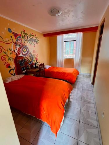 two beds with orange sheets in a room at Pakakuna in Urubamba