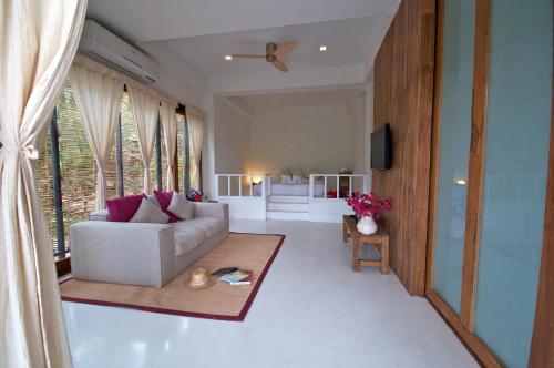 a living room with a white couch and a large window at Proud Phu Fah Maerim Resort in Mae Rim
