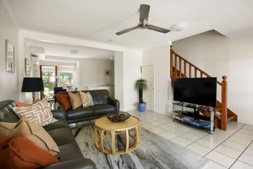 a living room with a couch and a flat screen tv at Riverside Rest on Noosa River in Noosaville