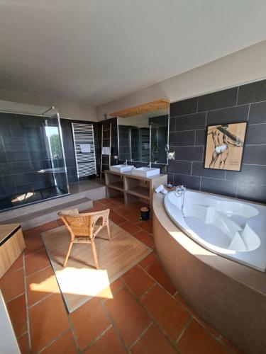 a large bathroom with a tub and a table and a chair at Maison Bacchus 31 in Buzet-sur-Tarn