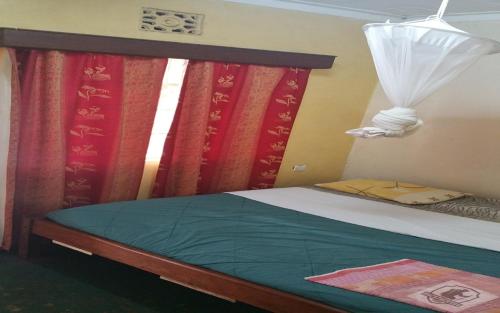 a bedroom with a bed with red curtains and a window at Mamba Village Kisumu in Kisumu