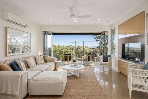 a living room with a couch and a tv at Townhouse with Private Magnesium Pool in Noosa Heads