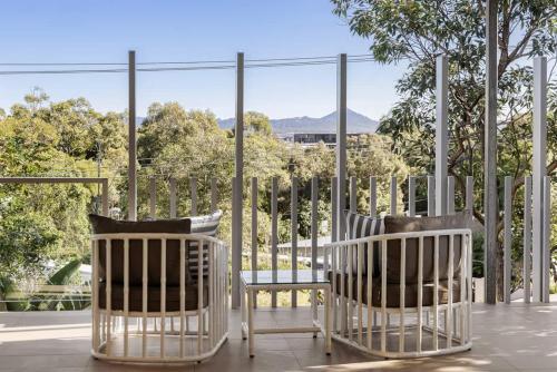 two white chairs and a table on a porch at Townhouse with Private Magnesium Pool in Noosa Heads