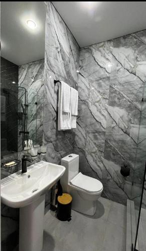 a bathroom with a white toilet and a sink at Van park hotel in Shymkent