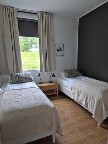 two beds in a bedroom with a window at Seydisfjördur Apartment in Seyðisfjörður