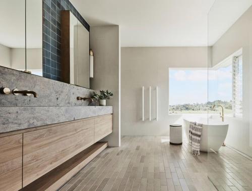 a bathroom with a tub and a large window at Byron Retreat in Coopers Shoot