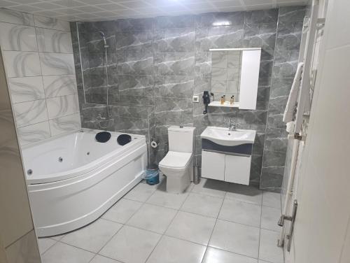 a bathroom with a tub and a toilet and a sink at Çiçek Hotel in Ankara