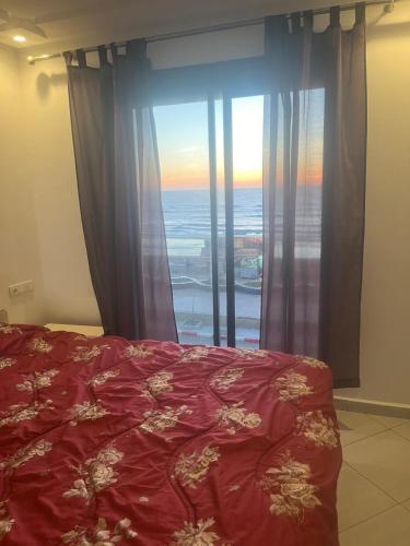 a bedroom with a red bed and a large window at Perle de LAtlantique in Kenitra