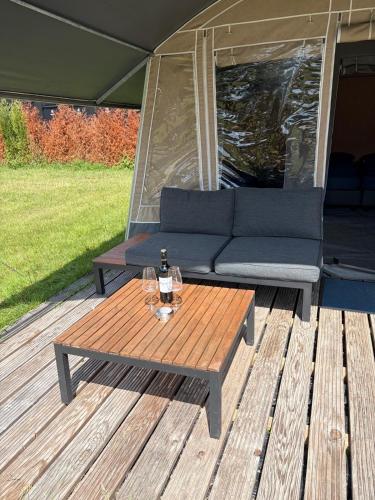 a couch and a table on a wooden deck at Glamping in Style in Dronrijp