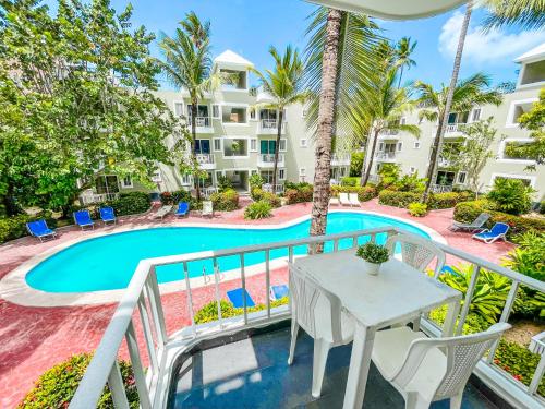 a balcony with a table and chairs next to a swimming pool at Tropical Adventure Studios Suites HOTEL Beach CLUB & SPA in Punta Cana