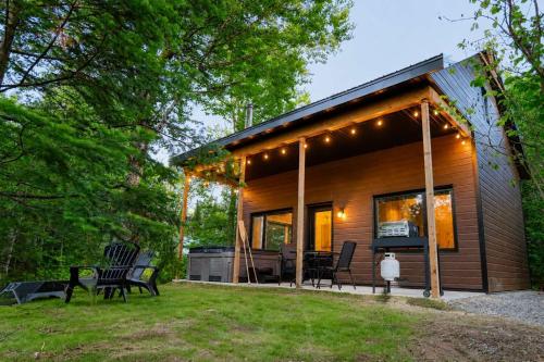 a log cabin with a grill and chairs in the yard at Le Colvert - Waterfront Cabin with Spa in Valcartier Station
