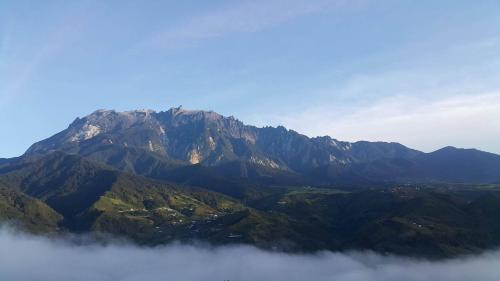 a mountain obscured by a layer of fog in the foreground at Crystal Hill R in Kundasang