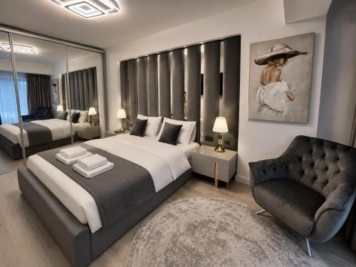 a bedroom with a large bed and a chair at INFINITY Sea View Luxury SUITE in Mamaia Sat/Năvodari