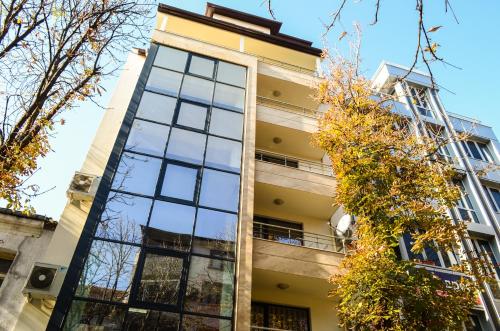 a tall building with glass windows and trees at Main Street Apartment in Sandanski