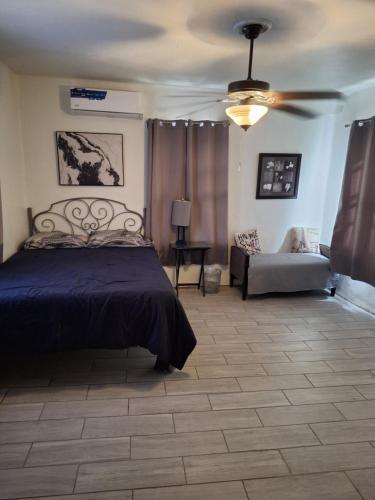 a bedroom with a bed and a couch and a ceiling fan at Casa en La zona Centro de la Ciudad in Ciudad Juárez