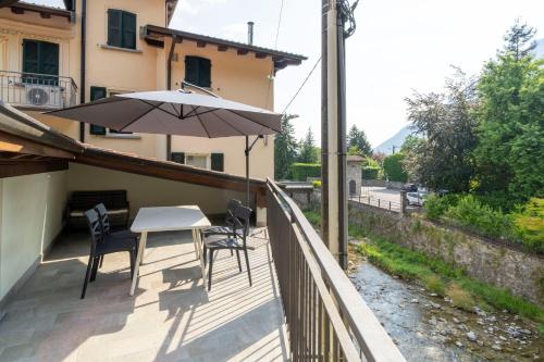 a balcony with a table and chairs and an umbrella at Mirafiume - Lugano Lake in Valsolda