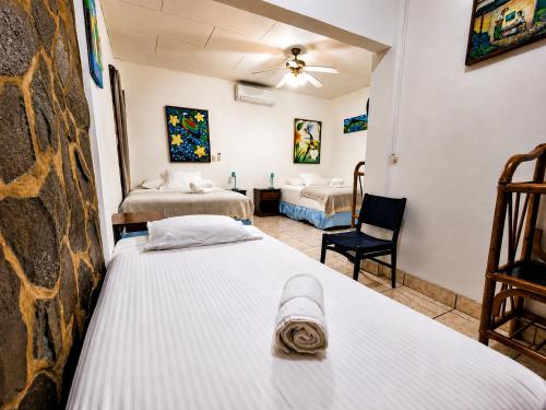 a room with two beds and a chair in a room at Hotel Gracia in San Juan del Sur