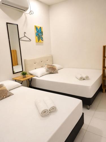 two beds in a room with a mirror at Hotel Riviera Central in Montería