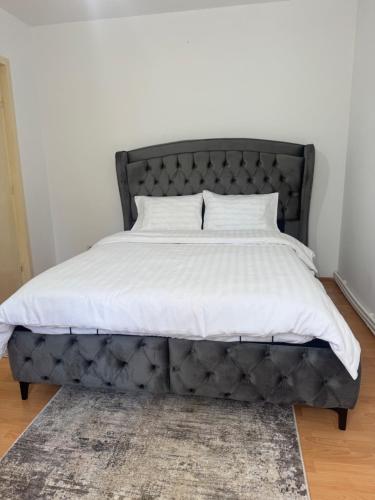 a bed with a gray headboard and white sheets at Apartament Central Pietonalul Unirii in Botoşani