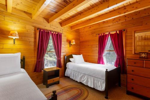 a bedroom with two beds in a log cabin at Rangeley Lake Resort in Rangeley